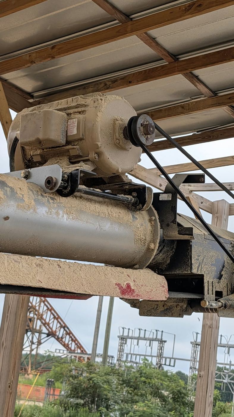 Motor and gearbox mounted on top of the auger conveyor, with the V-belt running down the side.