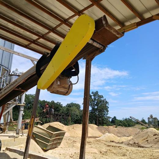 Yellow belt guard installed on a conveyor drive at a pellet plant.