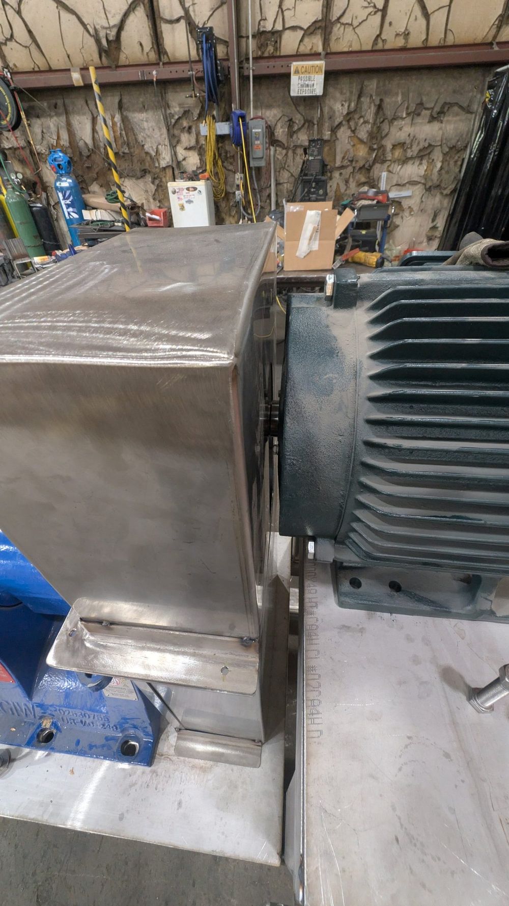 The stainless belt guard installed between the motor and the pump.
