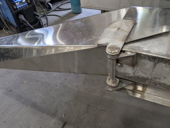 The built stainless hinge joining the chute to the machine frame.